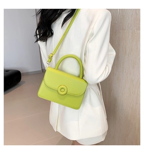 Crossbody view of a small neon green PU leather square bag with a golden round buckle