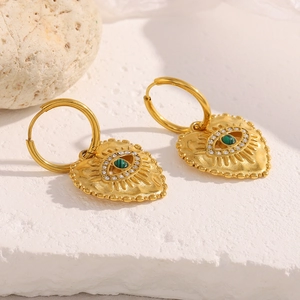 Detailed macro view of 18K gold evil eye heart earrings with malachite on marble