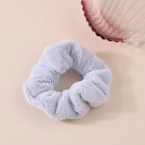 Dettaglio di un elastico per capelli in peluche viola chiaro su sfondo rosa