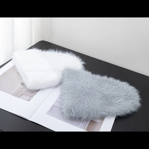 Close-up of fluffy mohair knit beanies in white and grey on a magazine backdrop