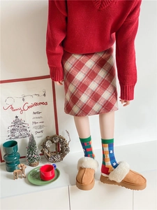 Close-up of festive Christmas socks with red sweater and brown suede slippers detail