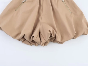 Dettaglio dei pantaloncini a palloncino kaki con tasche a zip e orlo a bolla elastico