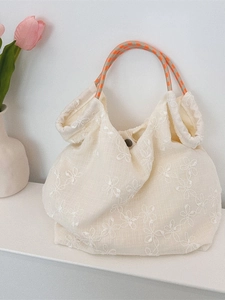 Floral embroidered canvas tote bag with colorful woven rope handles and metal snap button