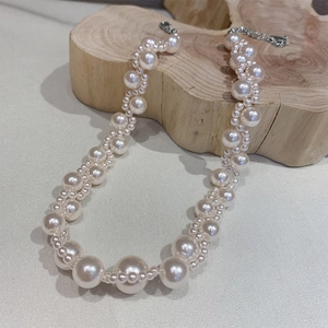 Elegant luxury pearl necklace with white pearls on a natural wood and beige fabric base