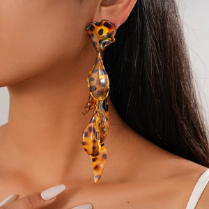 Close-up of tortoise shell acrylic petal tassel earrings on model with warm amber tones