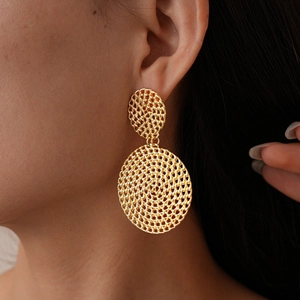 Gros plan de boucles d'oreilles dorées géométriques en résille portées par un mannequin