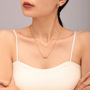 Collier double rang doré avec pendentif infini en zircon et petits breloques