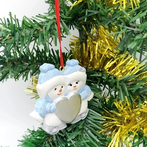 Detail of cute hugging snowmen Christmas tree ornament with blue hats and silver heart