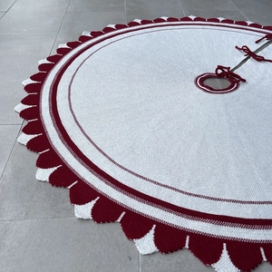 Dettaglio del tappeto per albero di Natale in maglia bianca con bordo smerlato rosso