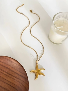 Detailed close-up of a 18K gold starfish pendant with textured finish on white background