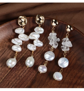 Detailed macro view of baroque pearl earrings on a premium silk fabric background