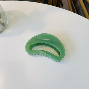 Detail view of crescent hair claw clip featuring green marble pattern and inner teeth
