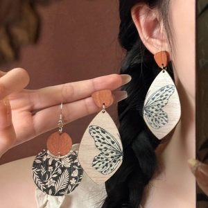 Close-up of vintage wood earrings with butterfly print and floral patterns on model