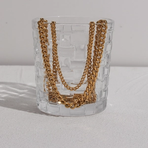 Dettaglio della catena cubana da 3mm placcata in oro 18K drappeggiata su un vetro ruvido