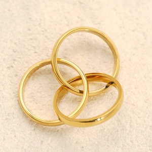 Polished 18k gold layered interlocking band ring set on a beige stone surface