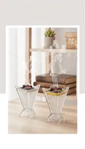 Close-up of crystal glass incense burners with gold and silver metal edges on wooden table