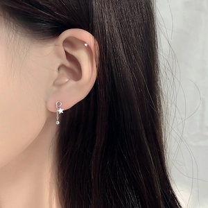 Detail shot of silver star stud earrings with hanging bead chain tassels on ear