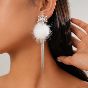 Close-up of snowflake pompom tassel earrings with sparkling crystals on female model