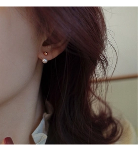 Close-up of minimalist freshwater pearl and gold bead earrings worn by a model