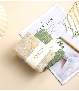 Close-up of A6 linen notebooks with floral embroidery and white paper bands