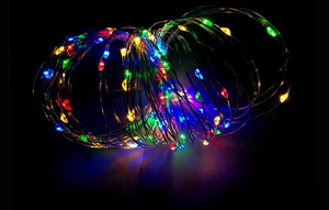 Close-up of multicolor battery powered LED fairy lights on copper wire with black background