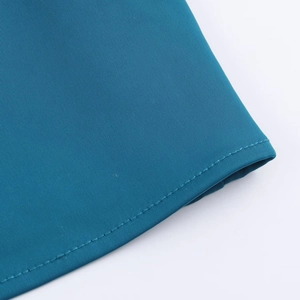 Vue macro d'un ourlet de robe midi bleu paon avec couture fine et texture satinée