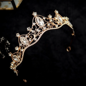 Detailed side view of a vintage gold tiara with marquise crystals on black velvet
