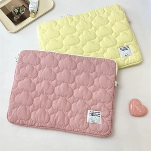 Detail of pink and yellow quilted cloud laptop sleeves with Cloud Hugger woven labels