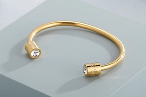 Detailed macro of golden C-shaped cuff bracelet with floral patterns and zircon studs