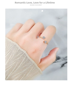 Detail of twisted rope gold band ring featuring double heart-shaped cubic zirconia