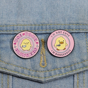 Funny yellow duck enamel pins with knife on denim jacket, featuring humorous text badges