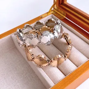 Vintage Armbänder in Gold und Silber mit geprägtem Kleeblatt-Muster auf einer Geschenkbox