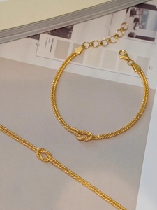 Close-up of golden S925 sterling silver Mobius knot double-chain bracelet on a book