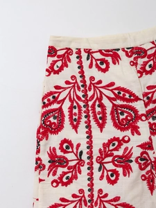 Détail macro d'une broderie ethnique rouge sur un short décontracté en coton blanc