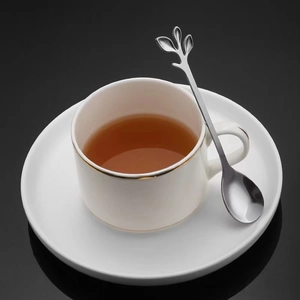 Minimalist leaf handle stainless steel spoon set with elegant white ceramic teacup and saucer