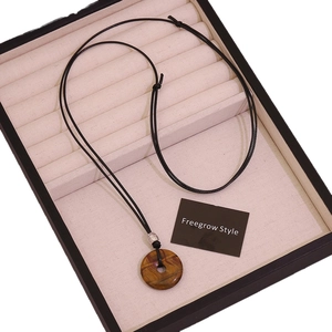 Adjustable black wax cord necklace featuring a tiger eye stone donut pendant in a jewelry box