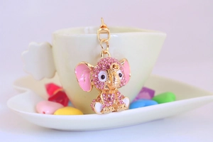 Close-up of cute pink crystal elephant keychain on gold metal with white heart prop