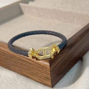 Dettaglio del bracciale intrecciato blu scuro con chiusura dorata e micro zirconi