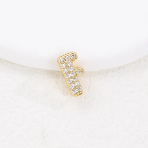 Macro view of gold letter F pendant featuring sparkling cubic zirconia stones on white texture