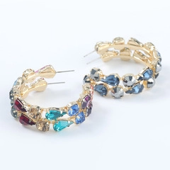 Detail of bohemian C-shaped earrings with colorful rhinestones and gold plating