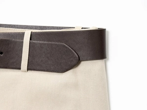 Gros plan sur ceinture en cuir marron foncé et coutures de pantalon en coton blanc