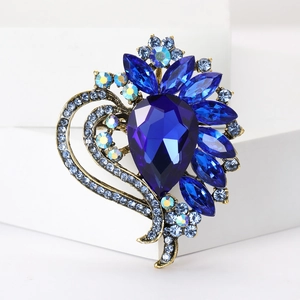 Detailed close-up of a blue crystal flower brooch with heart-shaped gold-tone metal base