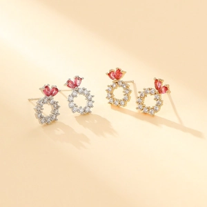 Detailed view of silver and gold snowflake stud earrings featuring red zircon hearts
