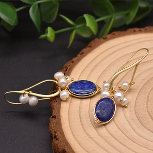 Macro shot of handmade wire-wrapped earrings with lapis lazuli and natural pearls