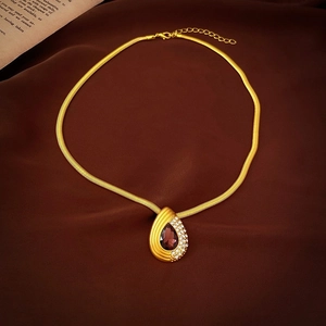 Dettaglio del ciondolo a goccia con pietra magenta e cristalli su catena serpente oro