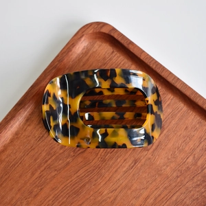 Detail of tortoiseshell acetate hair claw clip with hollow arch on a wooden tray