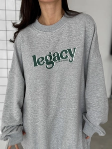 Detail of grey oversized sweatshirt showing cotton texture and printed legacy lettering
