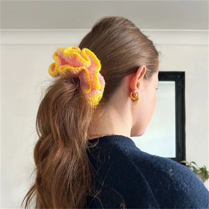 Close-up of a handmade crochet ruffle scrunchie in yellow and pink on a ponytail