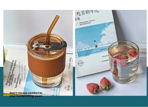 Close-up of amber glass coffee cup with brown leather sleeve and a glass straw
