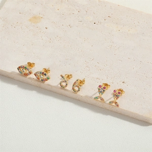 Detail of gold earrings set featuring evil eye and rainbow cubic zirconia stones